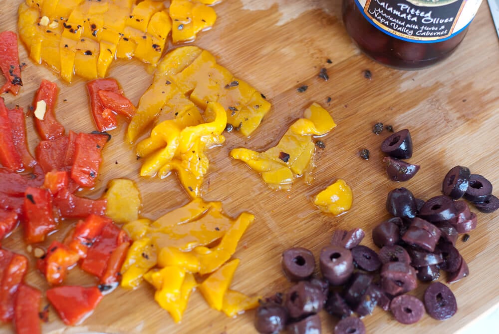 sliced roasted red and yellow peppers and olives for chickpea salad