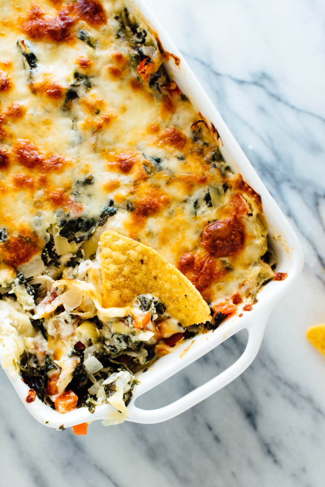 The best cheesy baked spinach artichoke dip, made lighter with extra veggies and no mayonnaise! Everyone will love this appetizer recipe.
