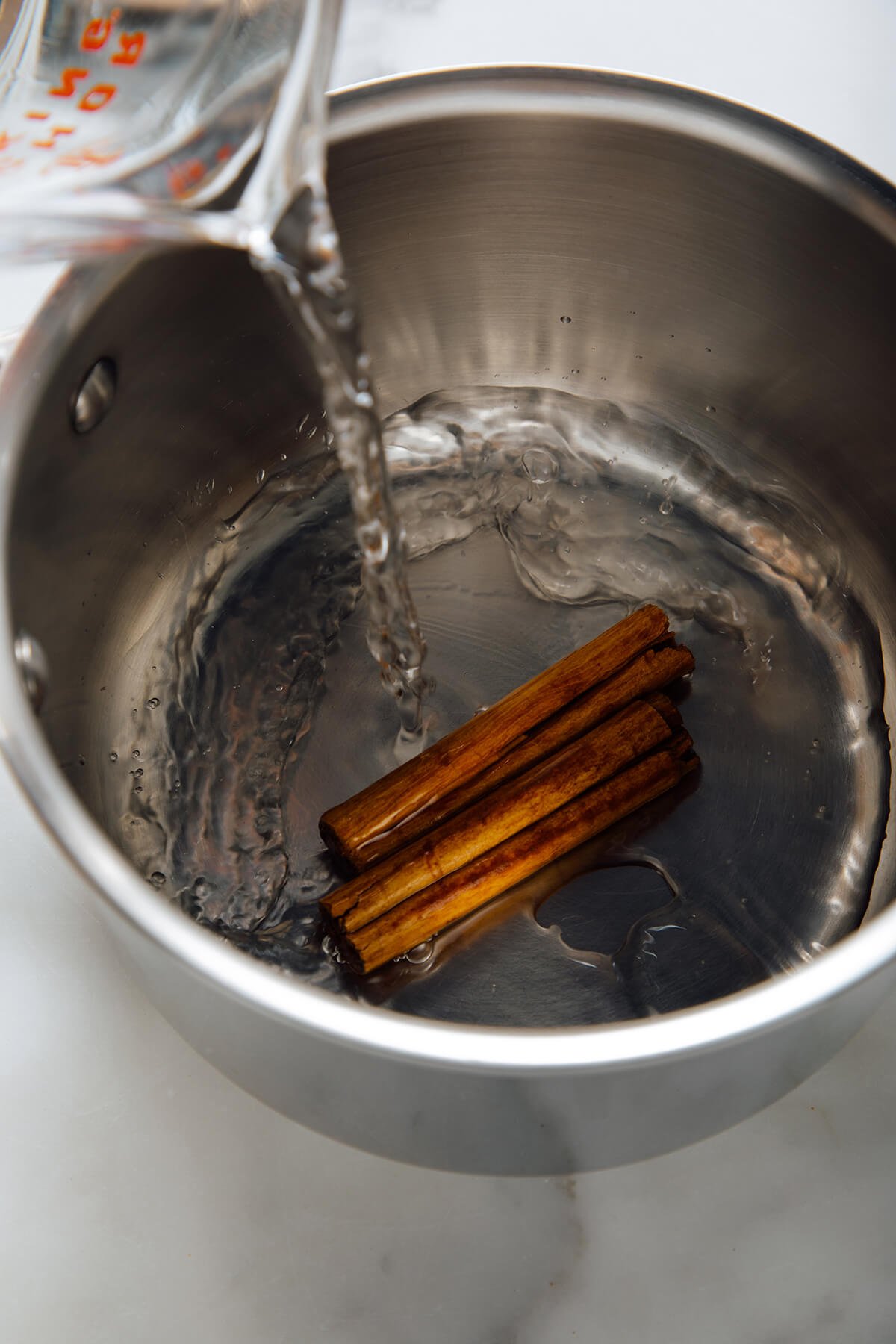 pouring water over cinnamon sticks