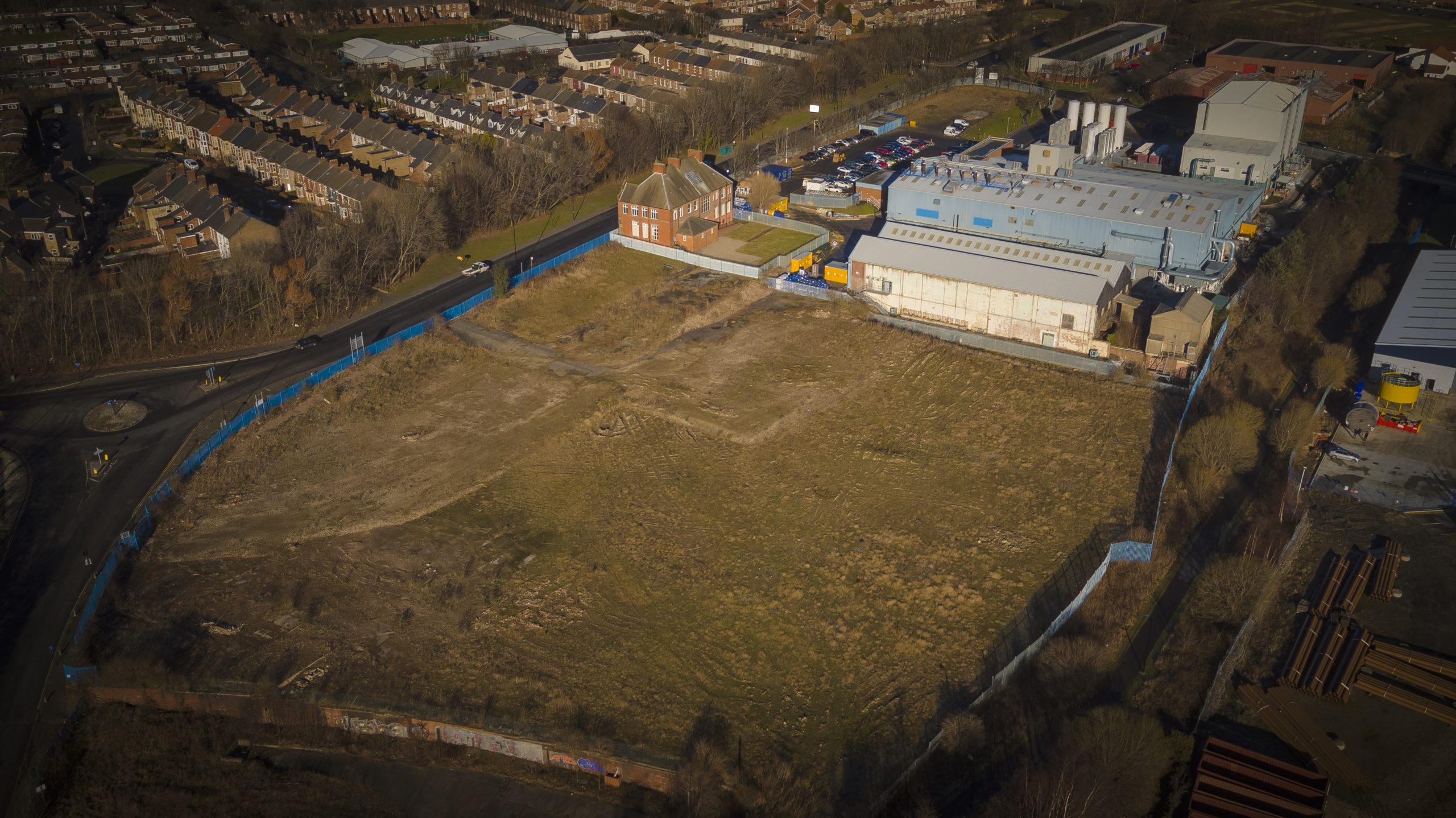 Aerial shot of the Neptune Park site, there is a large patch of grass with warehouse to the top right of the image.