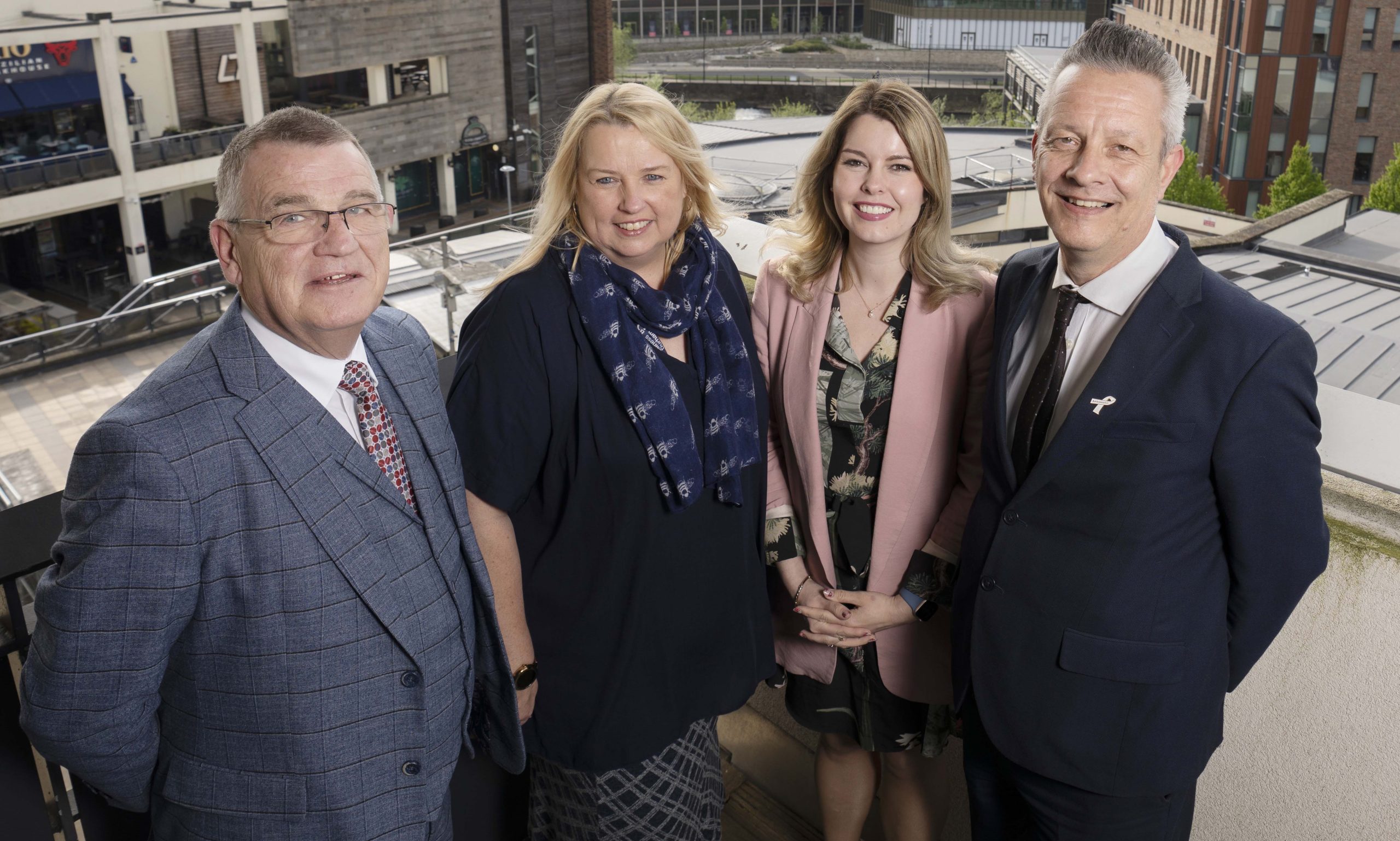 Four North East leaders stood on a balcony smiling to camera.
