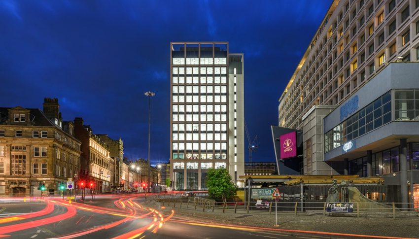 Image of Bank House office building at night with traffic speeding past in the foreground.