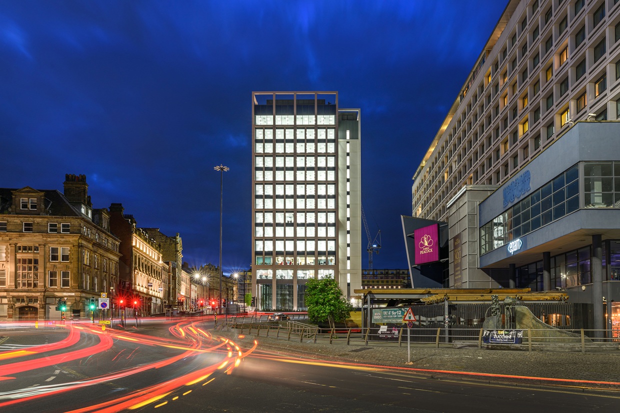 Image of Bank House office building at night with traffic speeding past in the foreground.